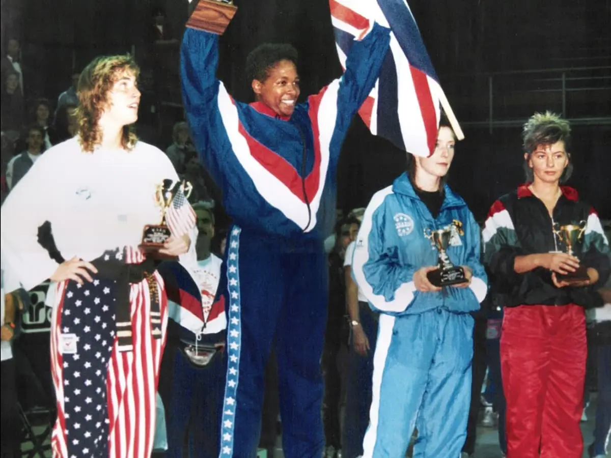 Denise Biley on a padium with a Union jack flag in celebration