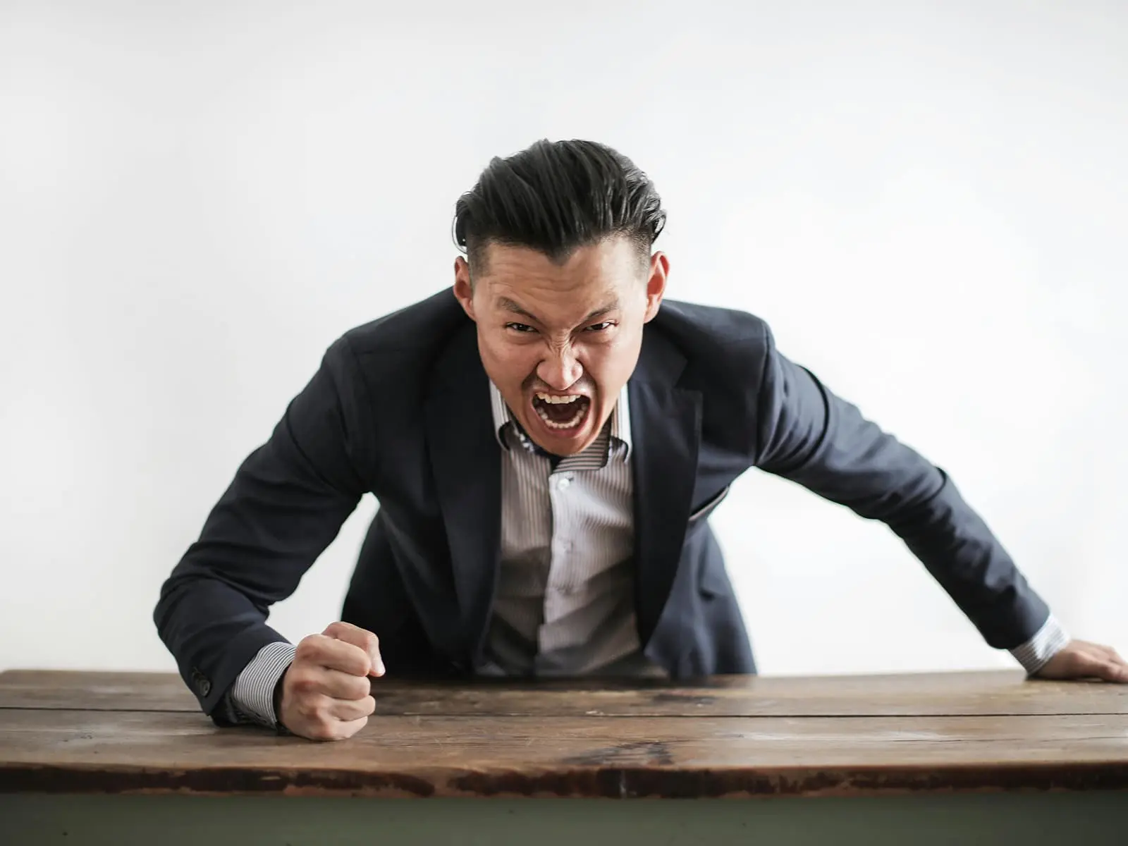 Angry person over a desk. Photo by Andrea Piacquadio