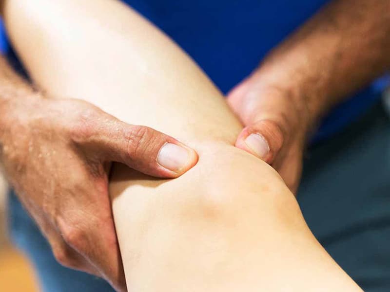 A knee in the hands of a masseur